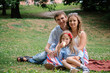 © natalia_4g - Family concept: woman, man and daughter sitting in the park. Summer outdoors