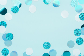 Wall Mural - Festive frame of iridescent confetti sparkling on pastel blue background. Holiday backdrop. Flat lay, copy space.