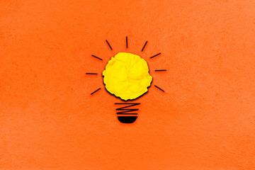 creative inspiration from yellow concept crumpled paper turn on light bulb metaphor for good idea concept on orange paper background / best solution think answer