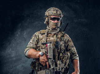 Wall Mural - Brave and strong military man in mask and sunglasses is holding his machine gun.