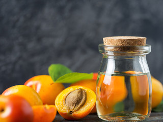 Close-up of apricot oil and fresh red apricots on wooden table