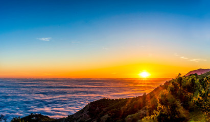 panorama of setting sun at sunset over layer of clouds