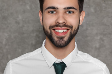 Portrait of confident businessman smiling on grey background, closeup