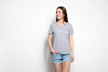 Sticker - Young woman in t-shirt on light background. Mock up for design