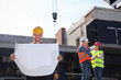 © New Africa - Foreman with drafting and professional engineers in safety equipment at construction site. Space for text