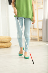 Blind person with long cane walking indoors, closeup