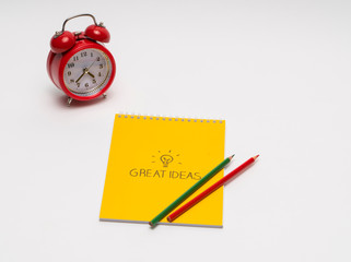 alarm clock with notepad and colored pencils on white background, isolated. back to school. great ideas