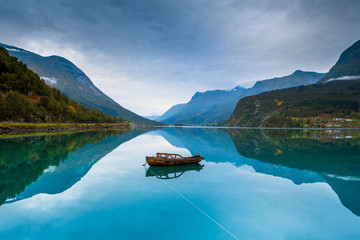 Little wooden boat on a calm lake in a Norway mountains.