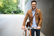 © NDABCREATIVITY - Happy young stylish businessman going to work by bike