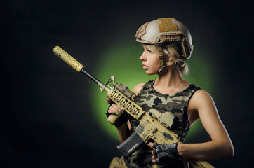 the girl in military overalls airsoft posing with a gun in his hands on a dark background in the haze