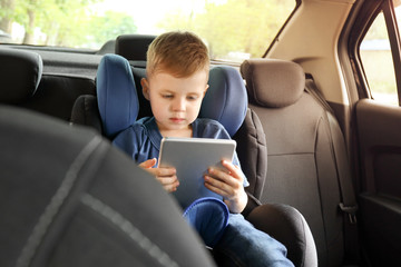 Canvas Print - Little boy with tablet computer buckled in car seat