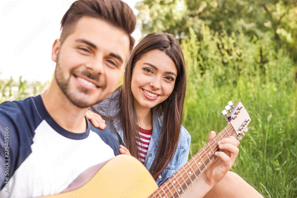 Young couple with guitar on picnic in park