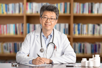 Asian male doctor sitting at desk smiling