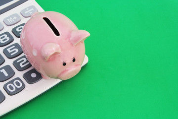 Piggy bank on calculator on green background with space for text, save money concept