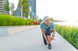 © Dragana Gordic - Female runner tying her shoes preparing for a run. Attractive senior fitness woman tying her shoelace outdoors.  Cheerful female athlete getting ready for workout wearing her shoes.