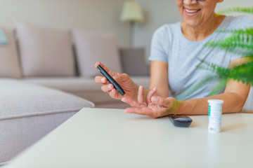 Wall Mural - Close-up photo with a woman who is testing her level of glucose in her blood. Diabetes doing blood glucose measurement. Woman using lancet and glucometer.