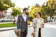 © Drobot Dean - Photo of affable office workers man and woman holding takeaway coffee while walking on city street