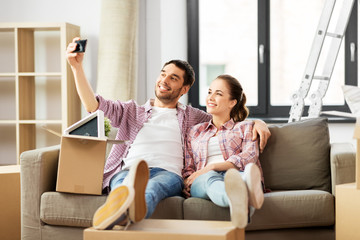 Sticker - moving, repair and real estate concept - smiling couple taking selfie by smartphone at new home