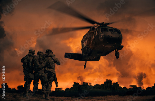 Fotomural 2 soldiers helping wounded soldier between dust in battle field to board the hel