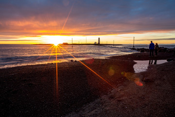 scenery colorful summer sunset over the sea, reykjavik, iceland. silhouettes figures of two tourists