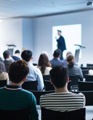 Fototapete - Seminar presenter at corporate conference giving speech. Speaker giving lecture to business audience. Executive manager leading discussion in hall during company training event. 