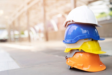 orange, yellow, blue and white hard safety wear helmet hat in the project at construction site building on concrete floor on city. helmet for workman as engineer or worker. concept safety first