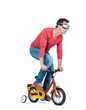 © afxhome - Funny man in goggles, jeans and a red t-shirt pedals a children's bicycle, isolated on white background.