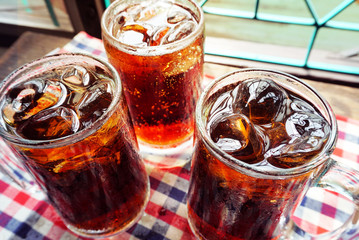 Wall Mural - Three glasses of cola with ice on table cloth.