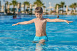 © Artem - Smiling Caucasian boy having fun in pool at resort. His hands are open wide.