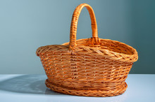 Wicker Basket, Lighted With Soft Daylight, Is On A White Surface. On The Background Of A Turquoise Wall