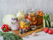 © senteliaolga - Cooking pickled vegetables. Salting various vegetables in glass jars for long-term storage. Preserves vegetables in glass jars. Variety fermented green vegetables on wood board