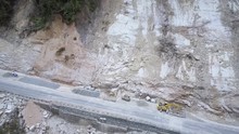 Building Equipment Restores Damaged Asphalt Road After Landslide At High Rocky Mountain Slope Foot Aerial View. Concept Global Warming Transport Routes And Annual Natural Disasters