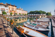 Old Harbour Full Of Boats In Desenzano Del Garda. Brescia, Lombardy, Italy. City Centre Of Desenzano Del Garda. Marina On Lake Garda.