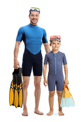 Wall Mural - Child and man in wetsuits standing and holding diving flippers