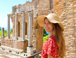 Portrait of young smiling woman with hat in famous Taormina Greek Theatre, Sicily, Italy