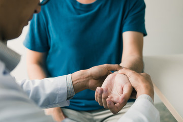 physical therapist checks the patient wrist by pressing the wrist bone in clinic room.