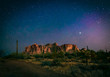 The desert wilderness east of Phoenix, Arizona photographed under clear starry desert skies that seem to glow with color. Desert plants and Saguaro cactus grow around the Superstition mountains 