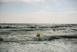 Fototapeta Tęcza - Buoy in the sea waves with foam. Empty beach. Summer vacations travel. Stormy ocean.