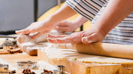 Family leisure and cooking hobby. Cropped shot of mother and daughter rolling dough in flour, making gingerbread biscuits.