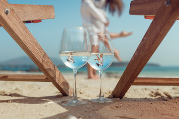 Two glasses reflecting the embracing couple on the beach. Honeymoon. Beautiful reflection in a glass of wine. Summer holidays. Tropical vacation