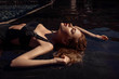 © Detkov D - fashion outdoor photo of beautiful girl with blond hair wears luxurious  black swimsuit, posing in the swimming pool. Luxury Female lying in the dark water