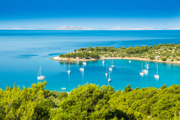 Panoramic view on Kosirina beach bay on Murter island in Croatia, anchored sailing boats and yachts on blue sea