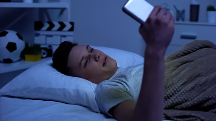 Teenager watching adult content on smartphone in the evening, puberty age