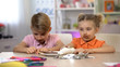 © motortion - Male and female kids smeared with chocolate sitting at table, harmful food