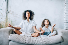 Cute Girl And Mother Meditating On Couch