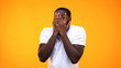 © motortion - Surprised afro american guy peeping through fingers against yellow background