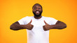 © motortion - Handsome black man smiling confidently, showing thumbs up on yellow background