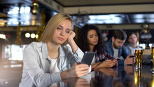 Group Of Friends Scrolling Phones Ignoring Live Communication In Bar, Addiction