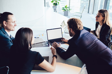 Wall Mural - Skilled group of employees searching information for startup project on modern netbook with mock up screen for advertise text, collaboration process, business people brainstorming at meeting in office