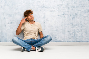 Wall Mural - Young african american man sitting on the floor with problems making suicide gesture